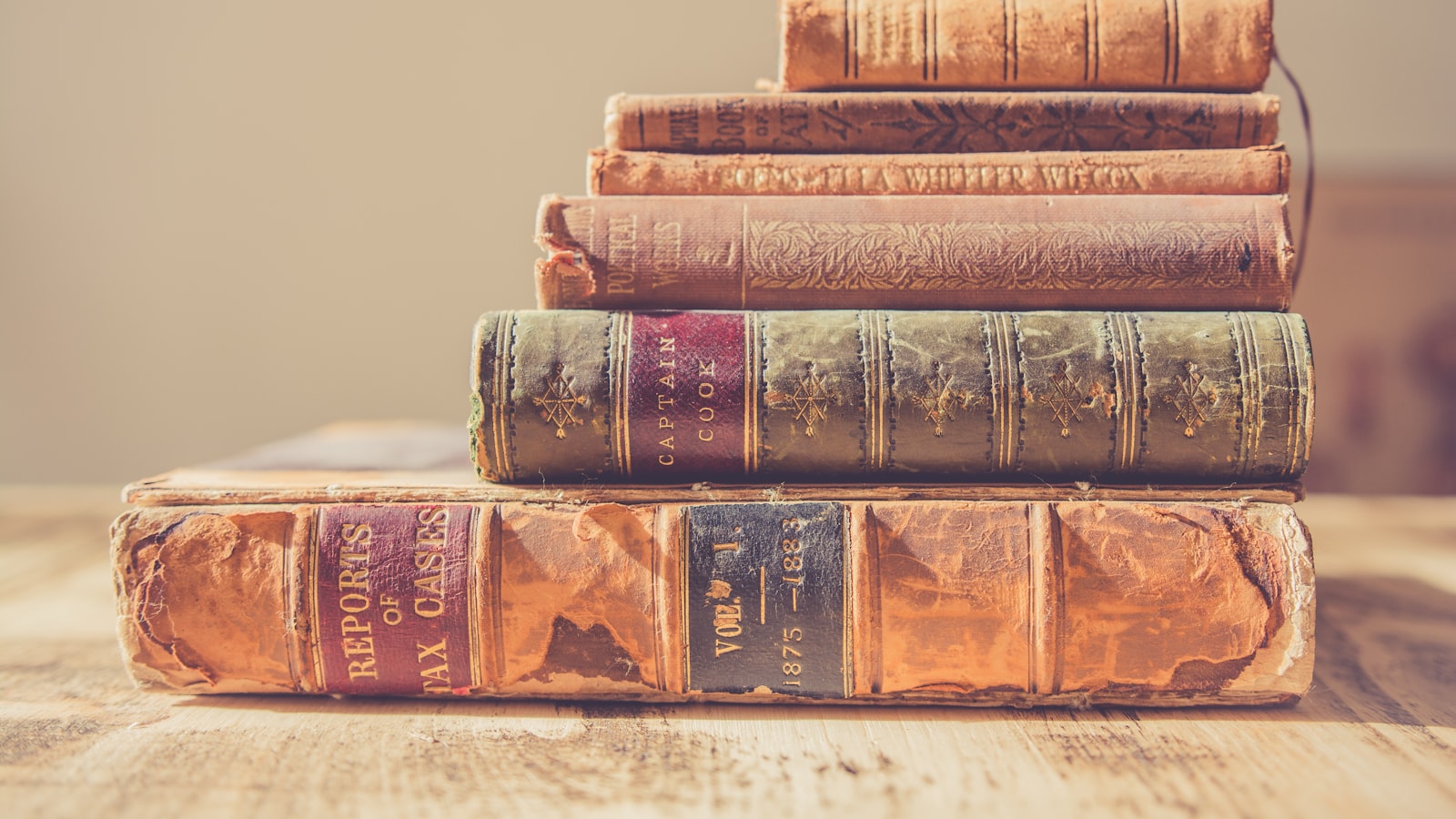 A thick open book with dense text on a desk lit by a lamp