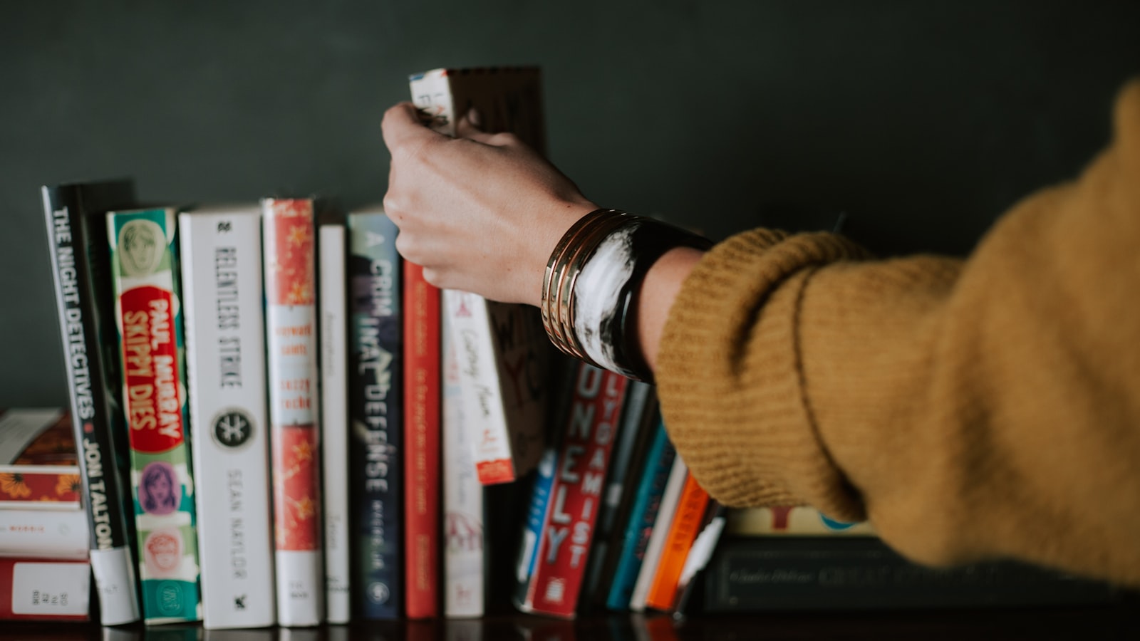 A book wrapped as a gift with ribbon beside a few loose books